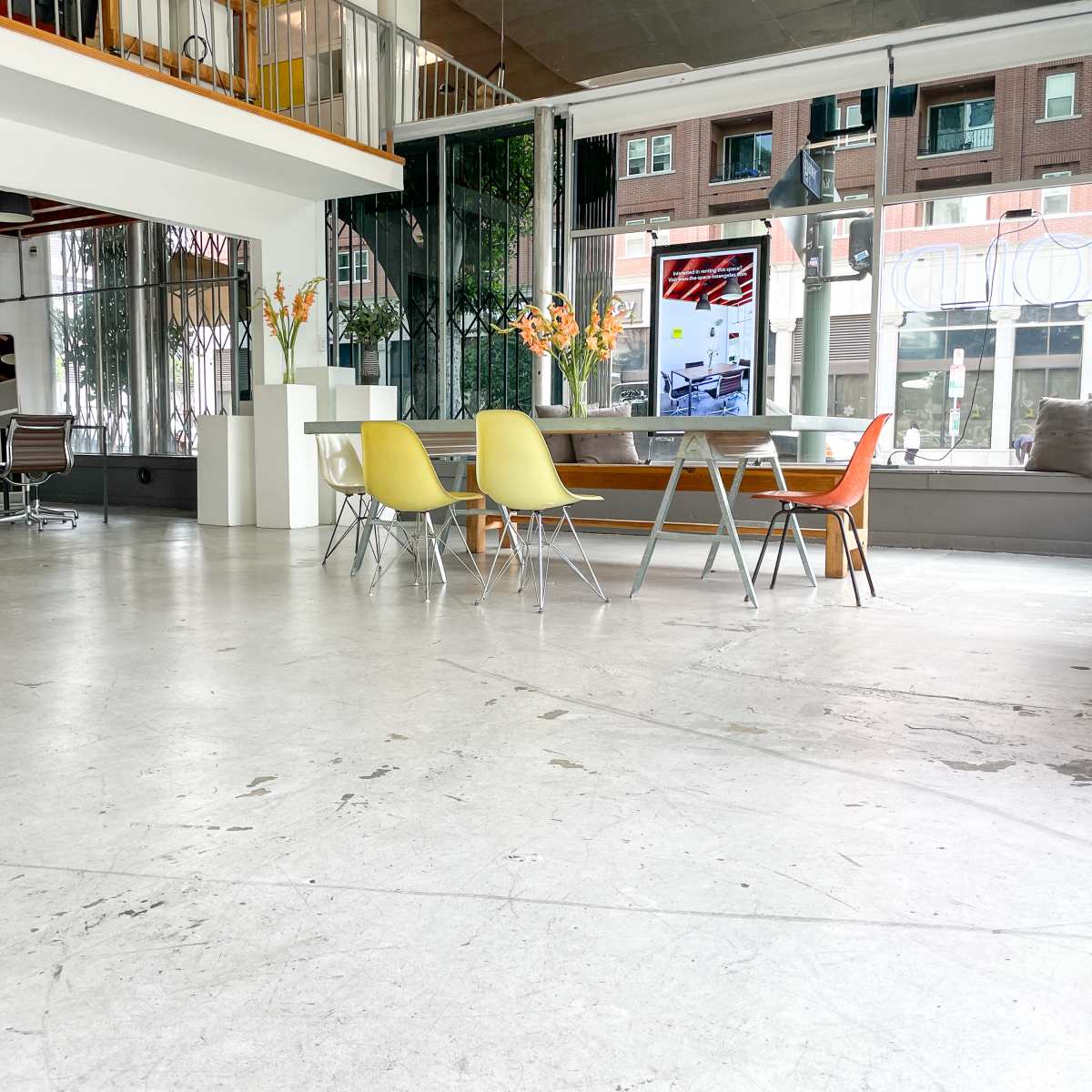 A spacious interior featuring a dining area with a large table and colorful chairs, surrounded by large windows and modern décor.