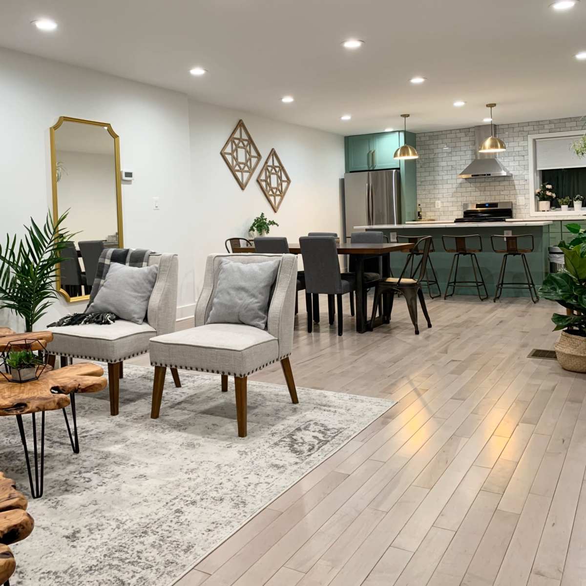 A modern living space featuring light-colored wood flooring, a dining area with a rectangular table, and seating arrangements that include two armchairs and a small coffee table.