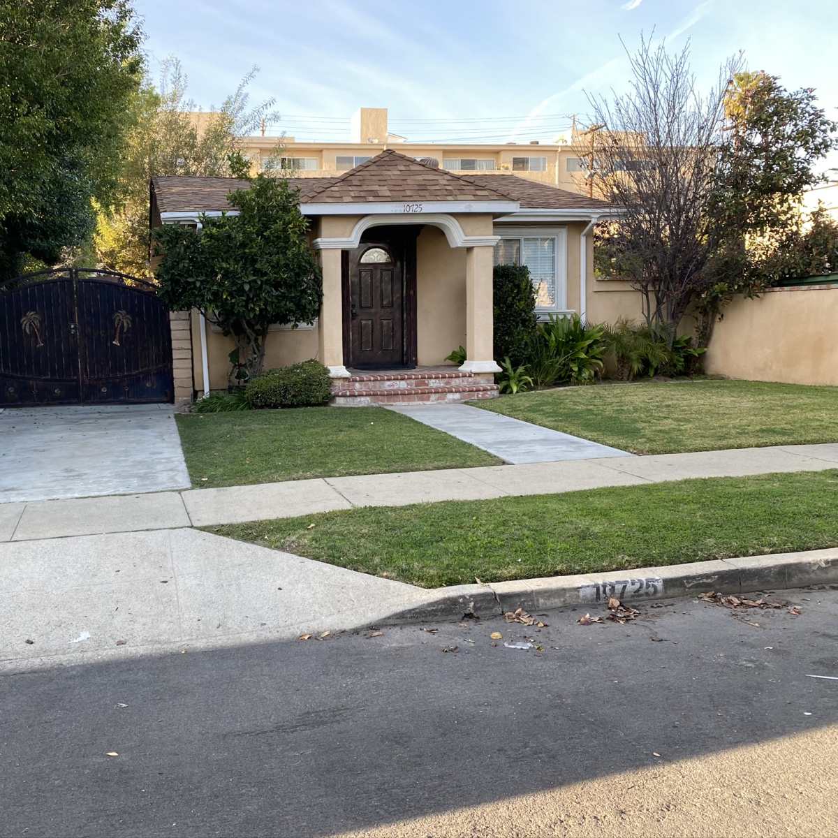 A single-story house with a landscaped front yard and a gated driveway is shown.