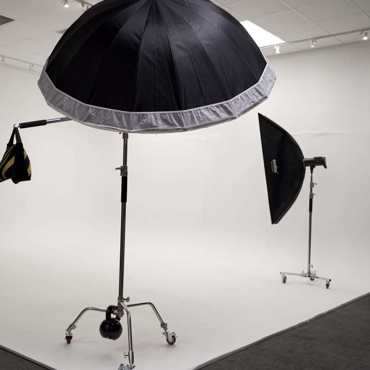 A photography studio with three lighting umbrellas positioned against a plain white backdrop.