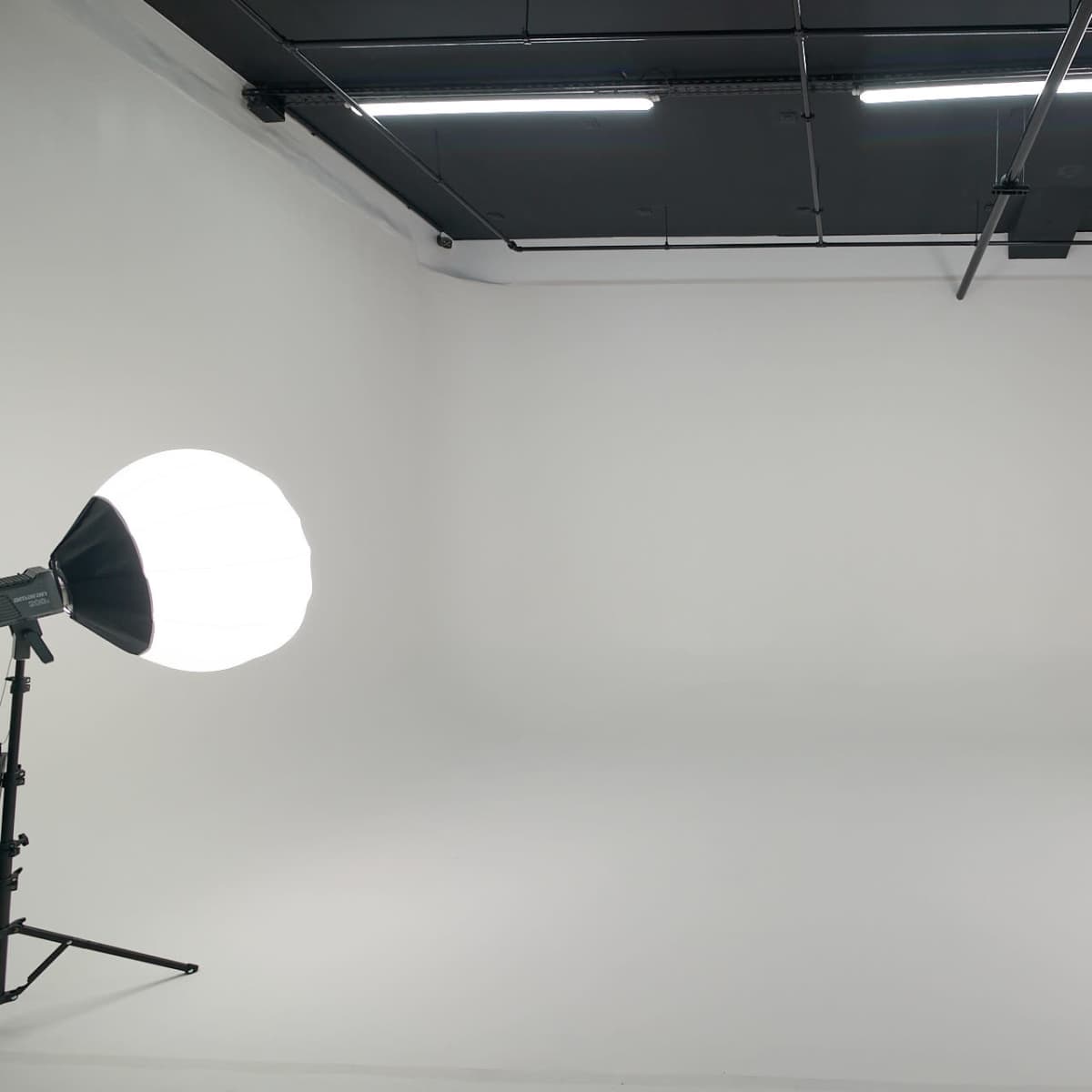 A spacious studio with a white backdrop and two softbox lights positioned on either side.