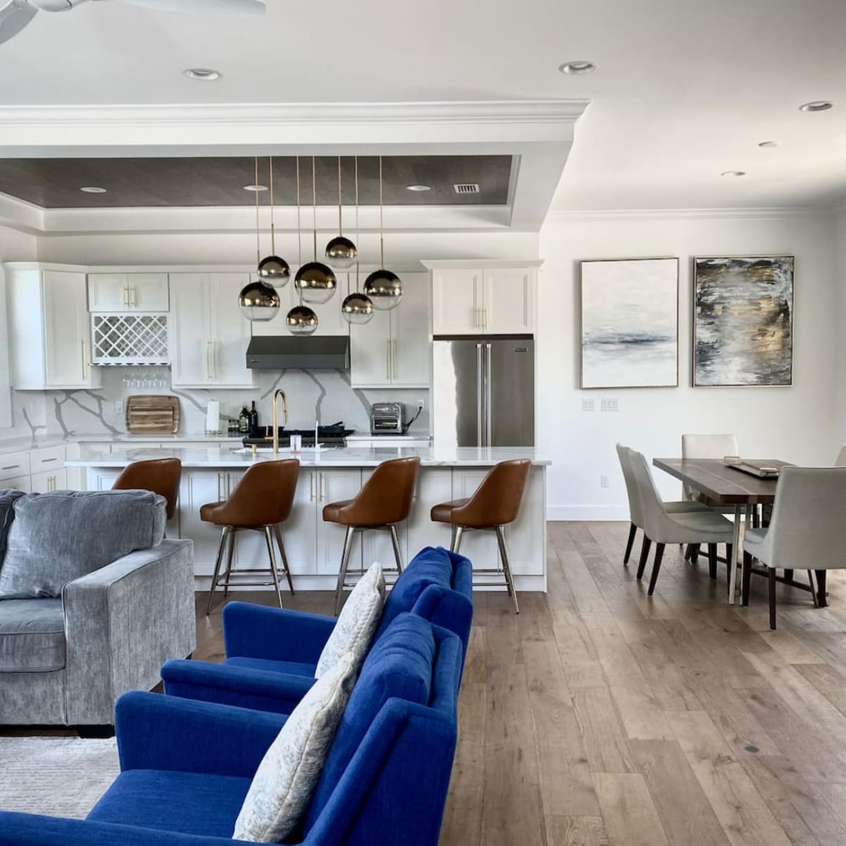 A modern kitchen and dining area with a seating arrangement, featuring a kitchen island with bar stools and a dining table nearby.