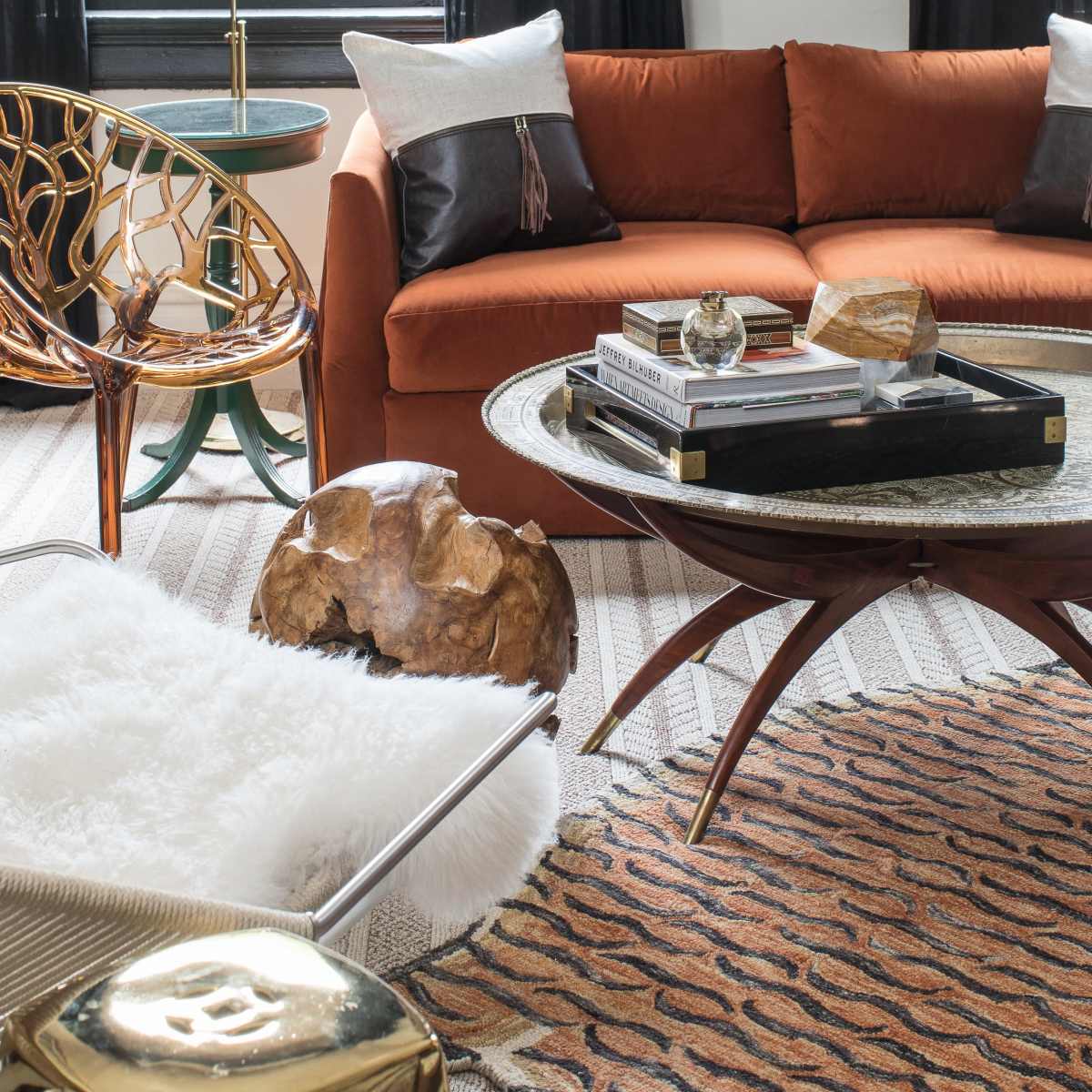 A cozy living room with an orange sofa, a round coffee table, decorative pillows, a rug, and unique accent chairs.