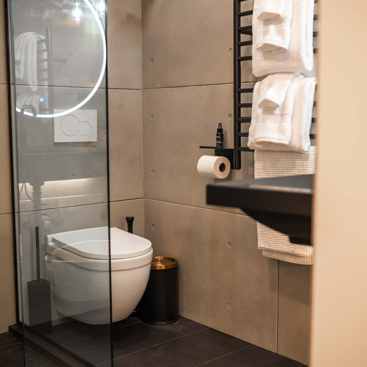 A modern bathroom featuring a glass shower, a white toilet, and neatly arranged towels.