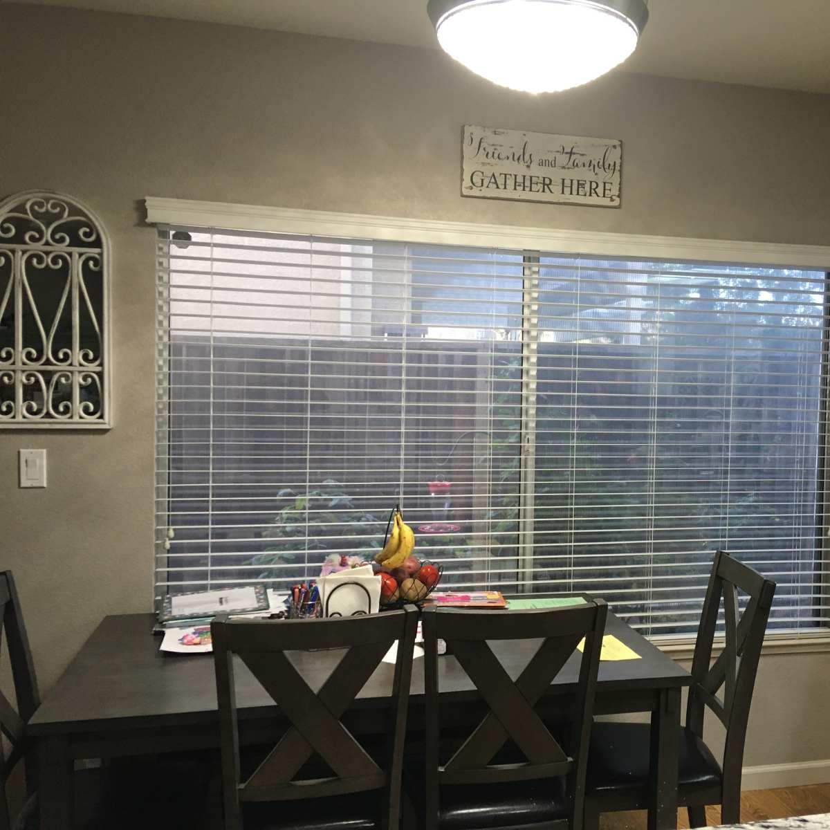 A kitchen features a dining table with chairs, a window with blinds, and a stove with cabinetry in the background.