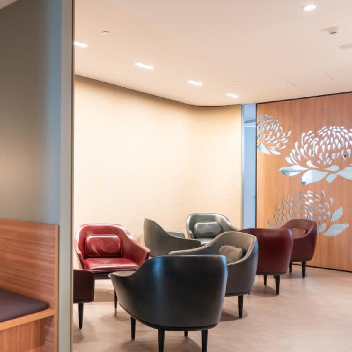 A modern lounge area featuring a cozy seating nook with a small table and a decorative wall, alongside a separate seating arrangement with contemporary chairs.
