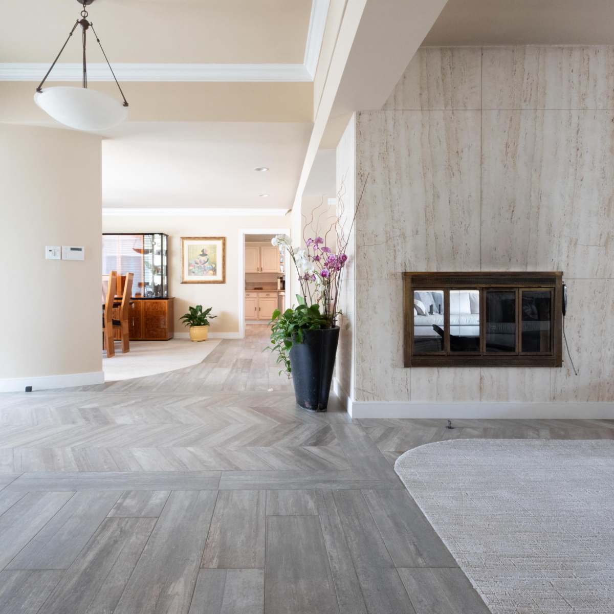 A spacious interior with a fireplace and a view into a dining area beyond.