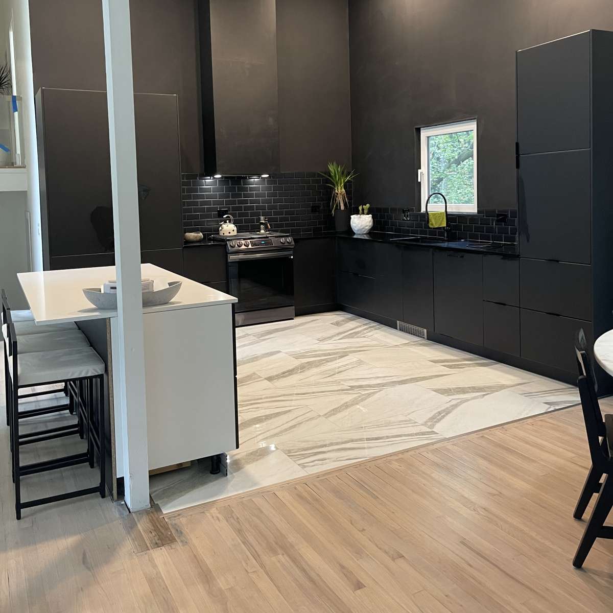 A modern kitchen with black cabinetry, a gas stove, and marble flooring.