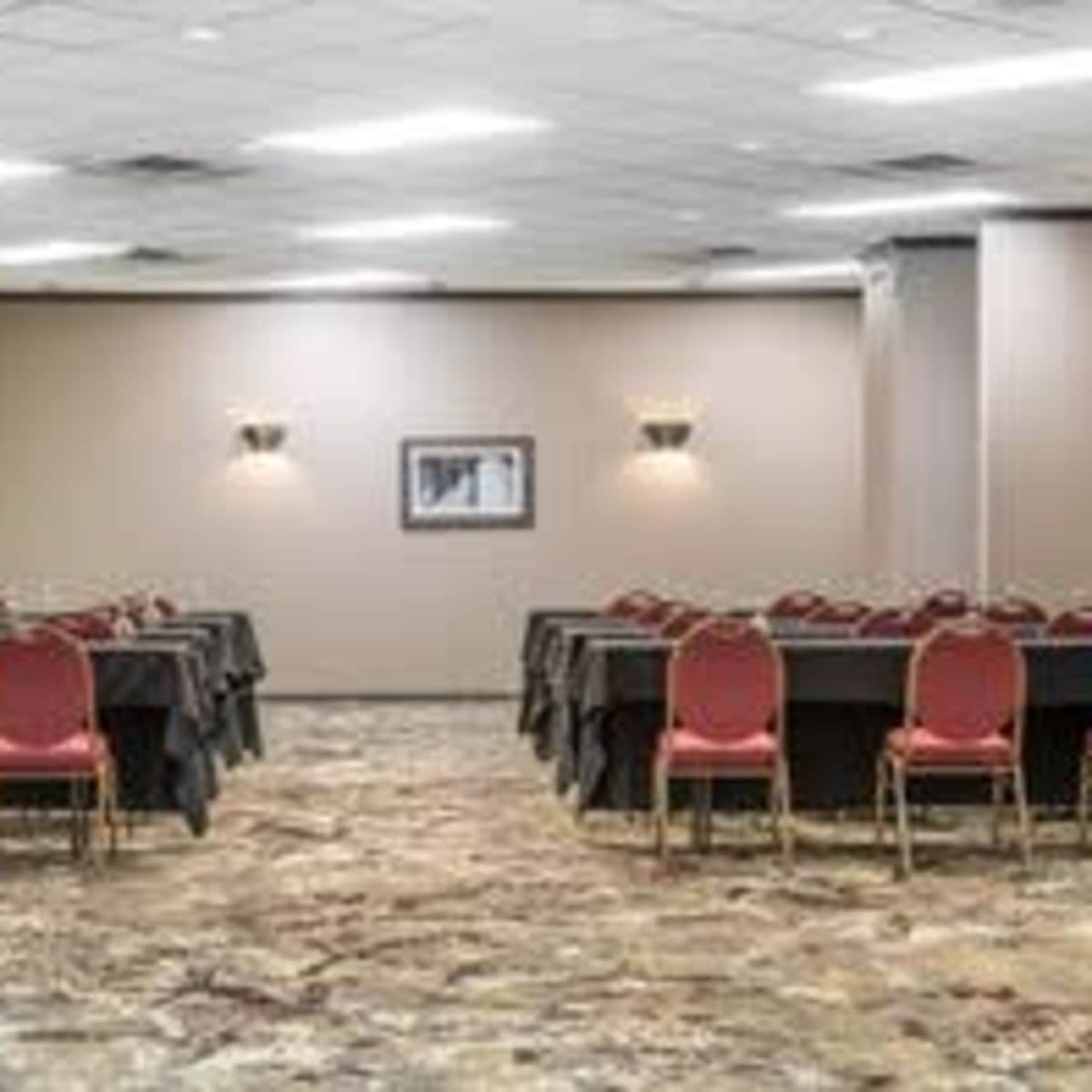 A conference room with two rows of tables and red chairs set up for a meeting.