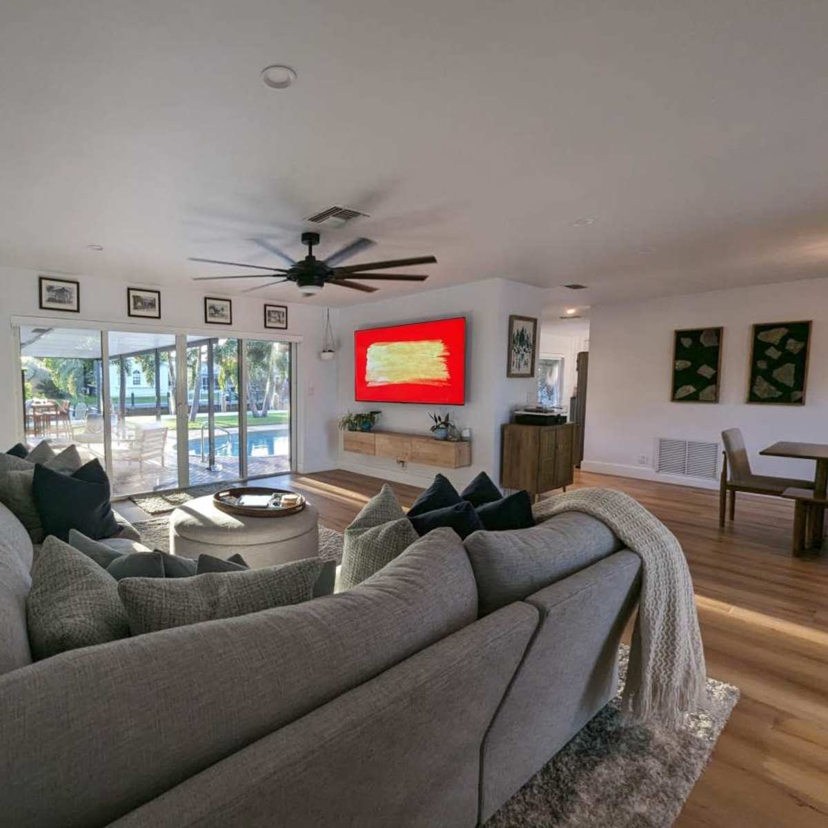 A modern living room with a large sectional sofa, a coffee table, and a view of an outdoor pool through sliding glass doors.