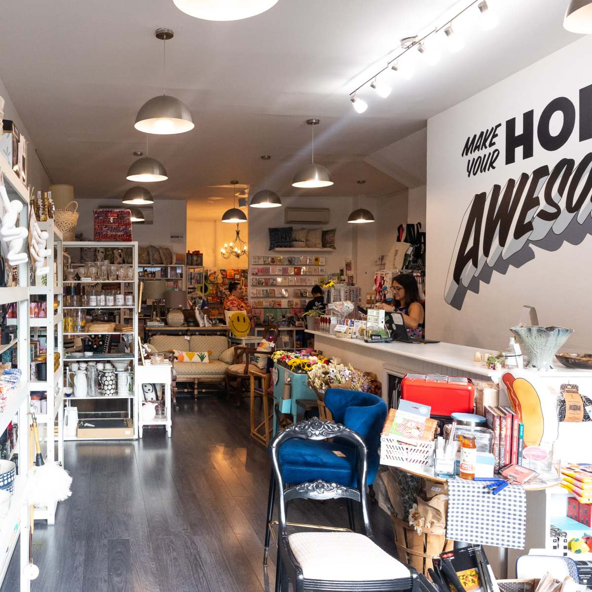 A retail store filled with various decorative items, kitchenware, and gift products, with shelves lining the walls and a checkout area at the back.
