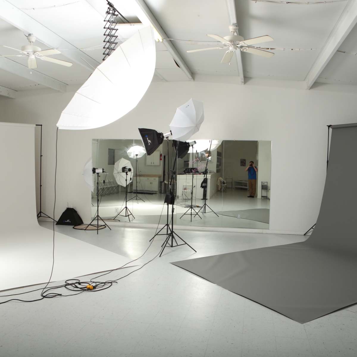 A photography studio with multiple backdrops, lighting equipment, and mirrors.