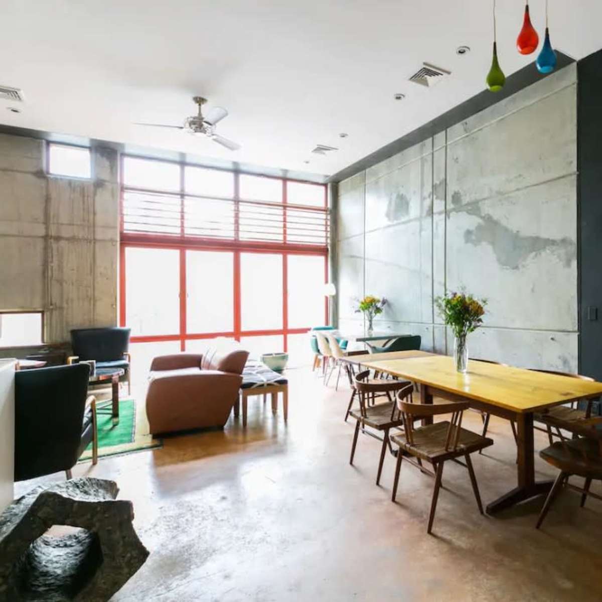 A modern interior space featuring a dining table, chairs, and large windows that allow natural light to fill the room.