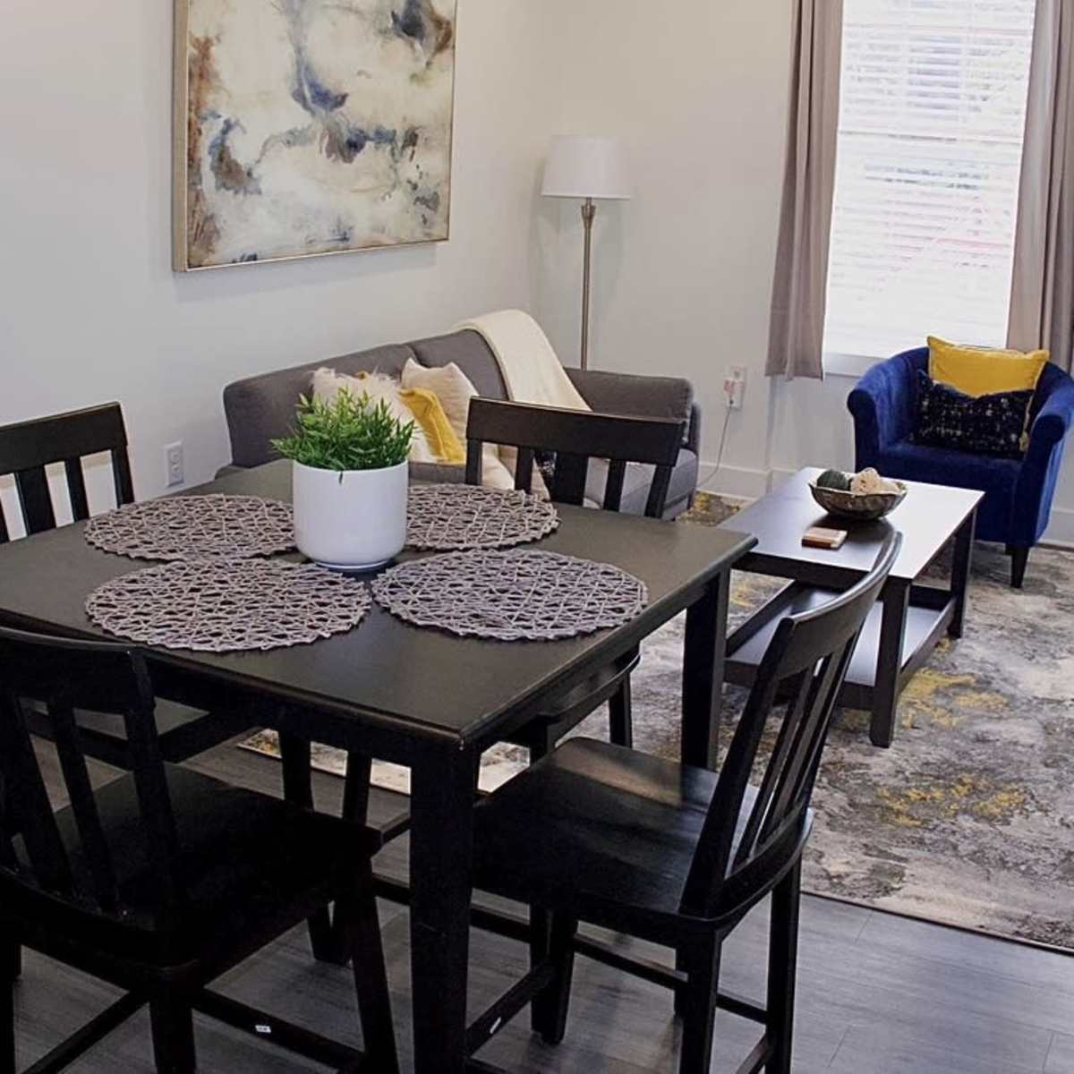 A modern living space with a dining table and chairs, a sofa, an armchair, and a decorative rug.