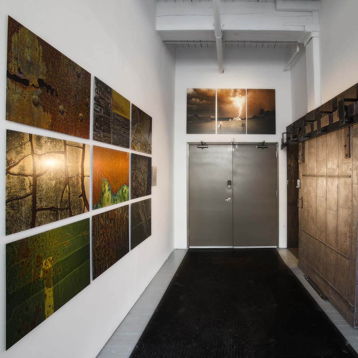 An interior hallway featuring large wall-mounted artwork, a pair of double doors, and a sliding wooden door on a track.