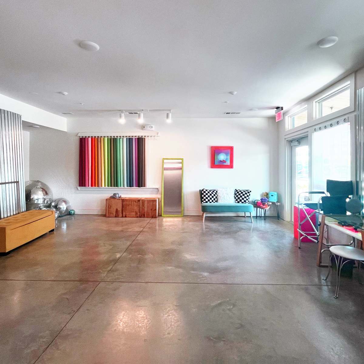 A spacious, brightly lit room with colorful artwork, a seating area, and polished concrete floors.