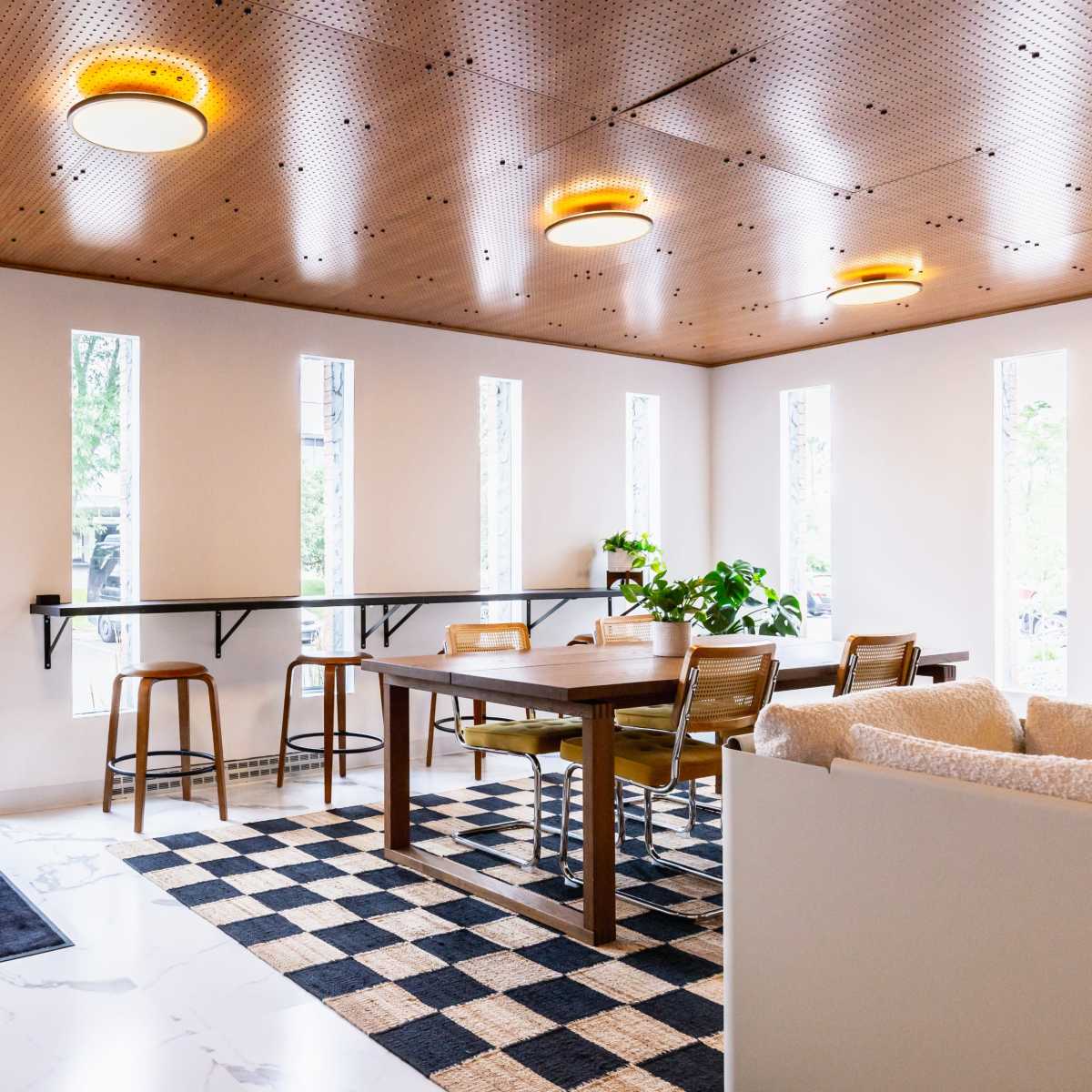 A modern interior space featuring a table with chairs, large windows, and a door leading outside.