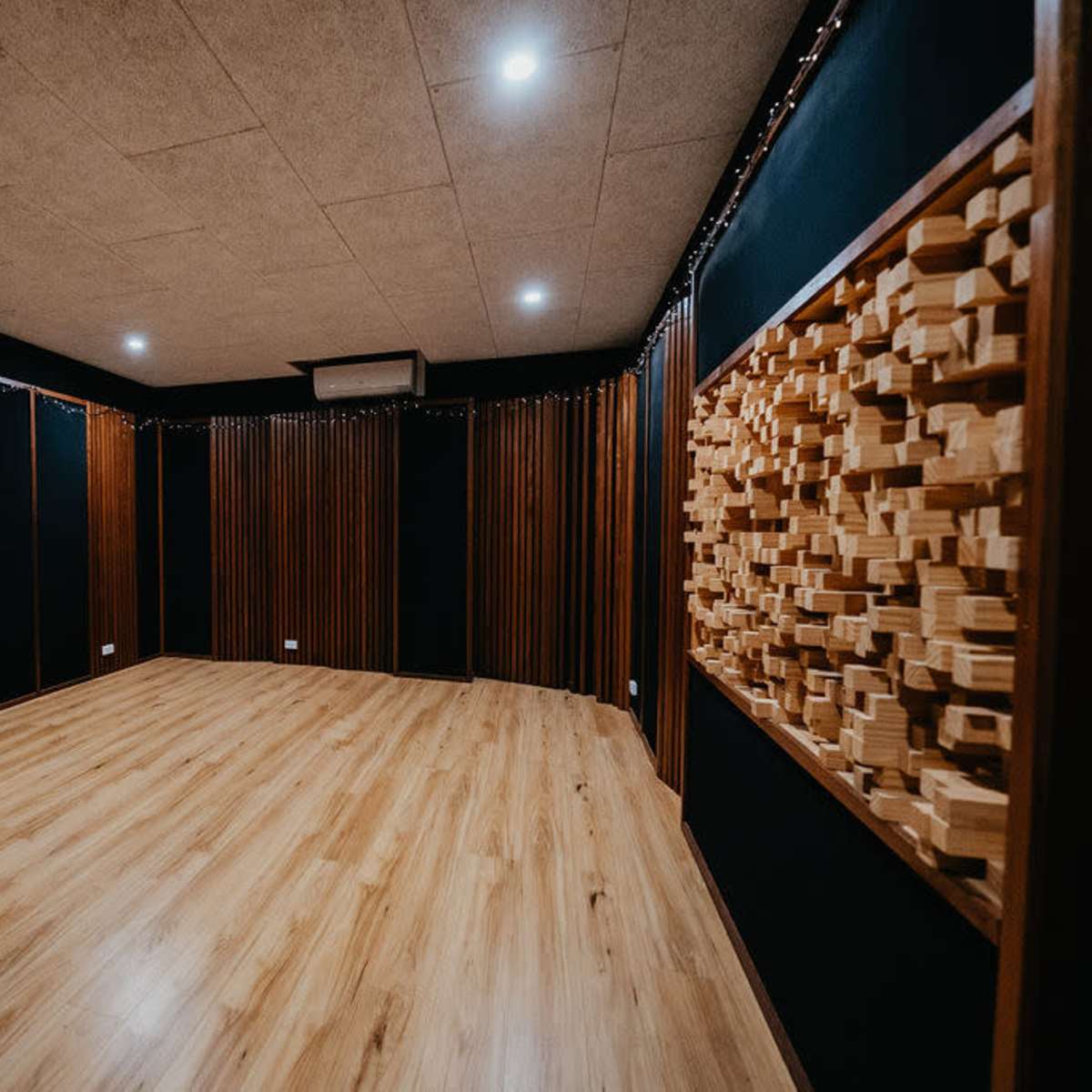 An empty soundproof recording studio with wooden paneling and a smooth wooden floor.