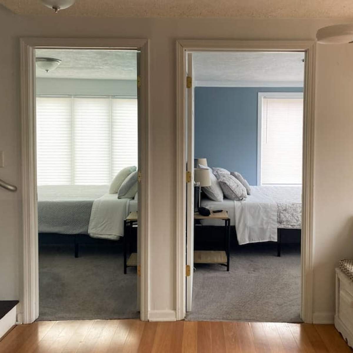 Two open doorways leading to two identical bedrooms with gray bedding and natural light filtering through window blinds.