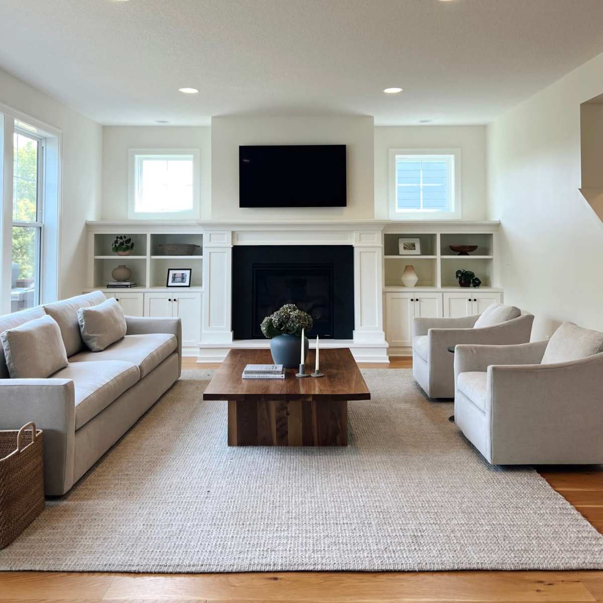 The living room features two light-colored sofas, a coffee table, and a fireplace with built-in shelves on either side.