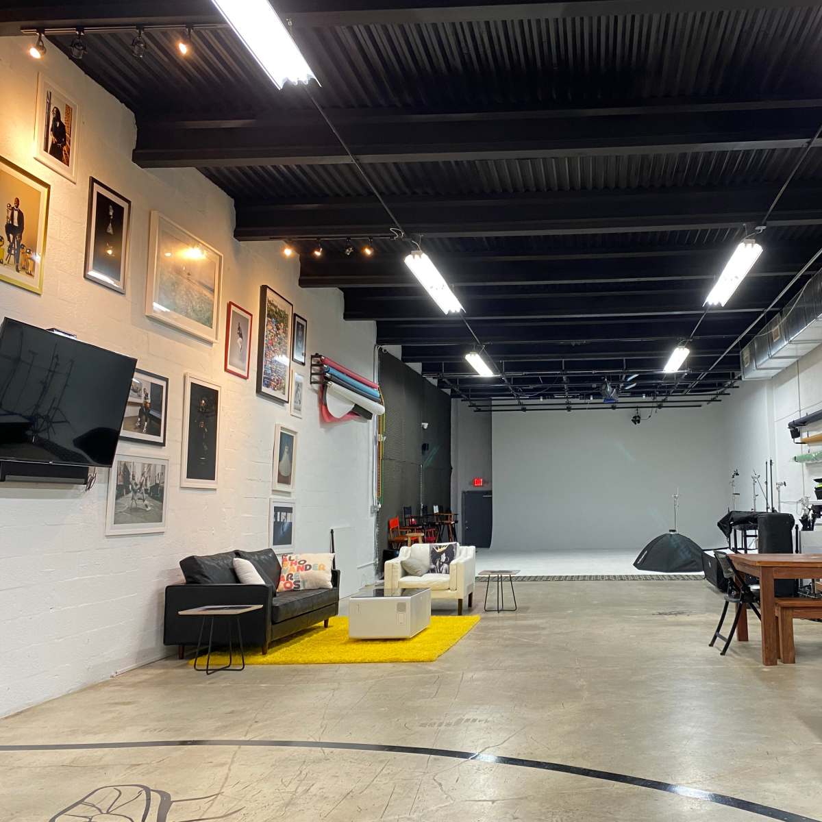A spacious studio with art on the walls, seating areas, and various equipment arranged around a large open floor.