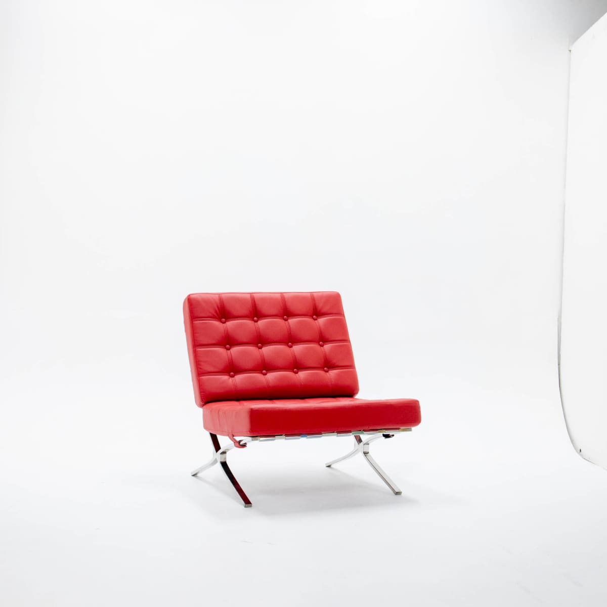 A red upholstered chair with a tufted design sits alone against a plain white background.
