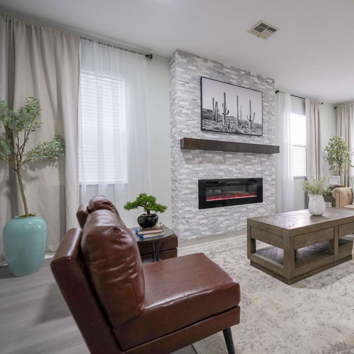 The living room features a modern design with a stone fireplace, a wooden coffee table, and comfortable seating arrangements.