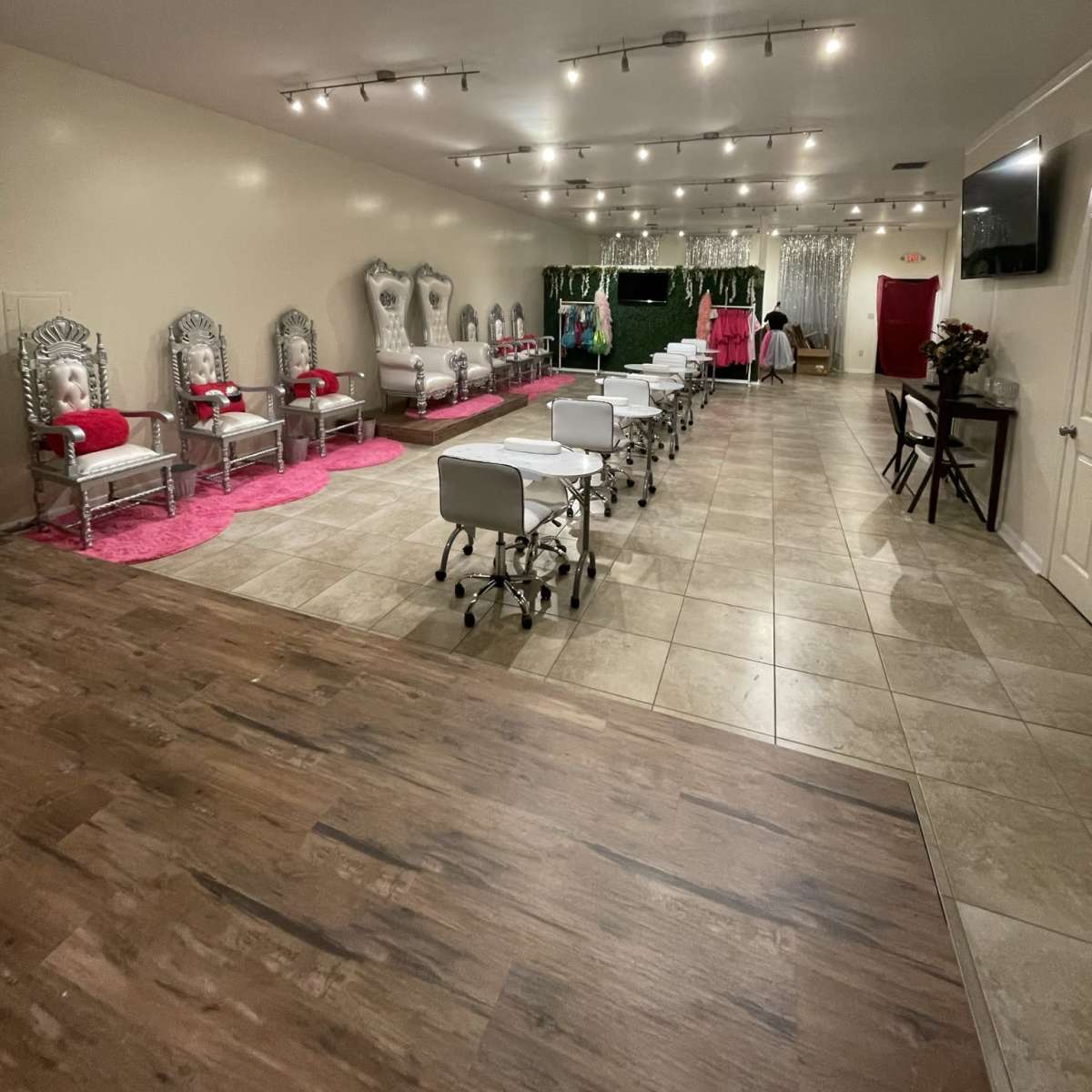 A spacious event room with silver chairs, white treatment tables on tiled flooring, and pink accents, including a plush pink carpet.