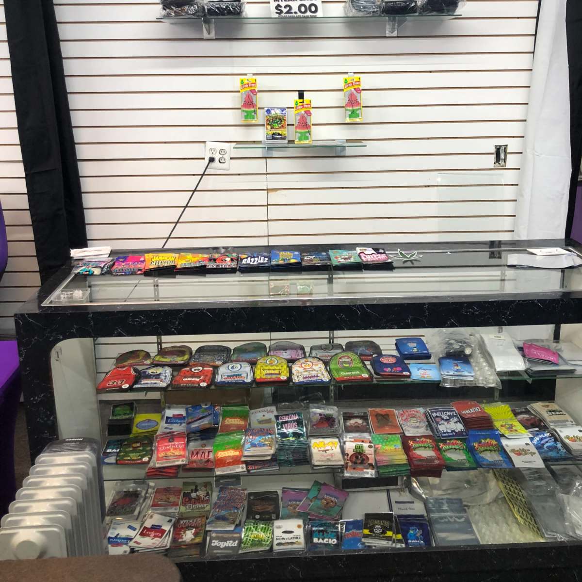 A display case filled with various products, including cards and personal items, with additional items displayed on shelves behind it.