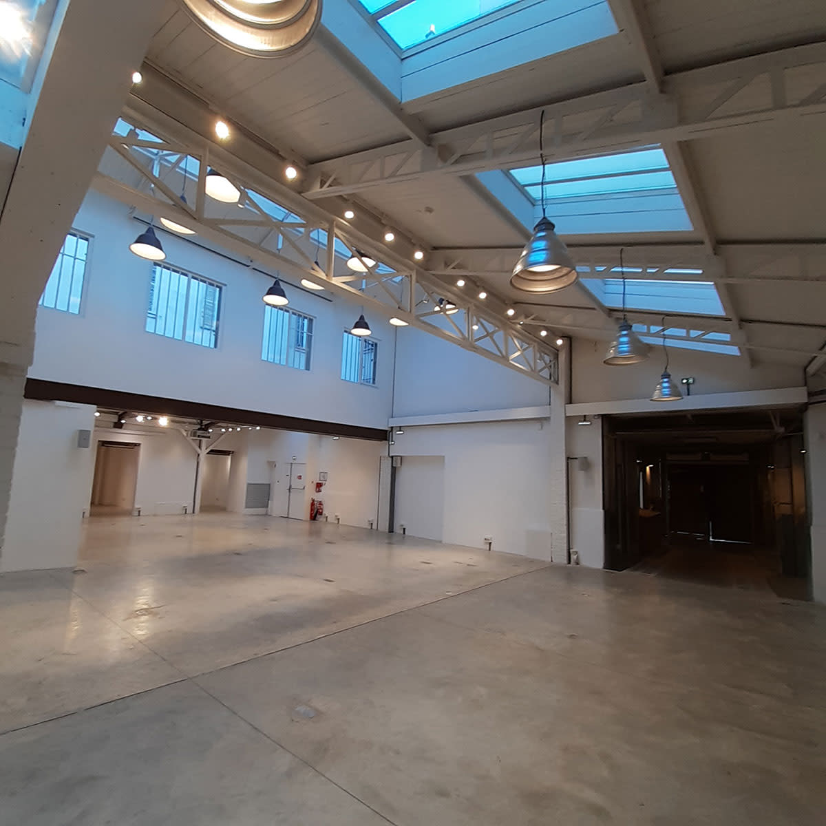 A spacious, empty warehouse with large windows and industrial lighting.