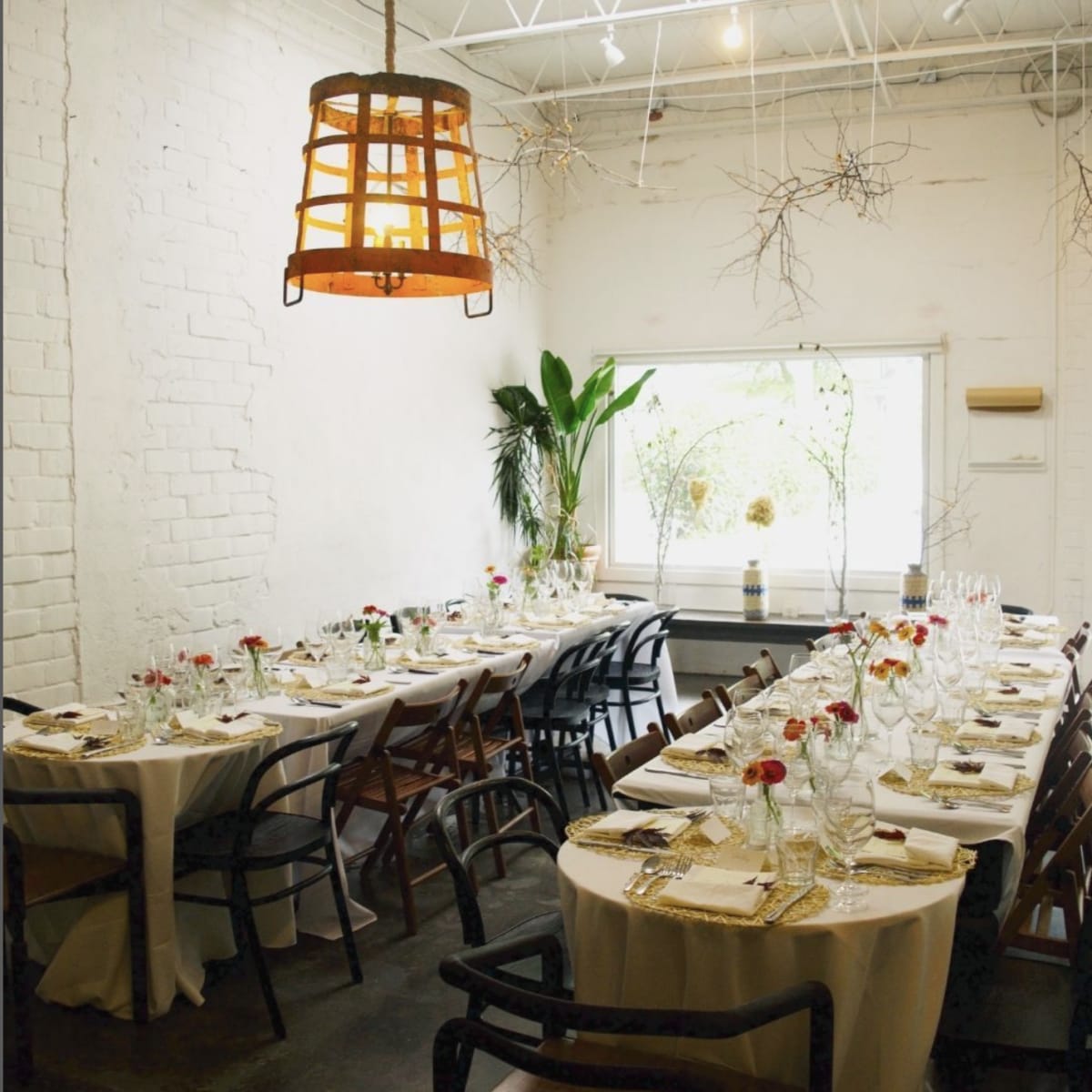 A spacious dining area features elegantly set tables with white tablecloths and floral centerpieces, illuminated by a hanging lantern above.