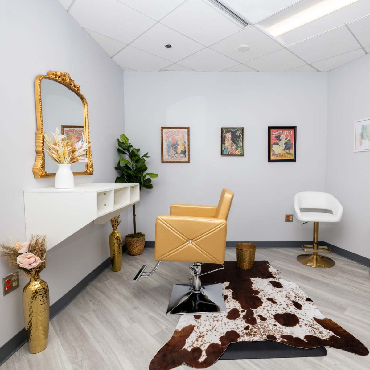 A modern interior space featuring a small vanity area with a mirror, an orange chair, two art pieces on the walls, and a cowhide rug on the floor.