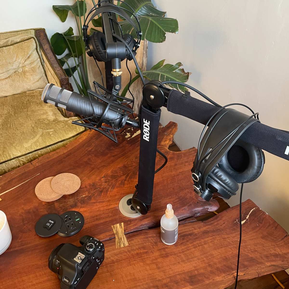 A wooden table with a microphone and headphones mounted on adjustable arms, along with a camera and other equipment nearby.
