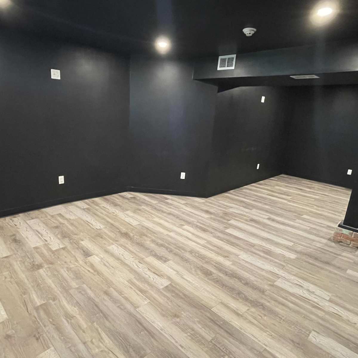 An empty room with black walls and light-colored flooring.