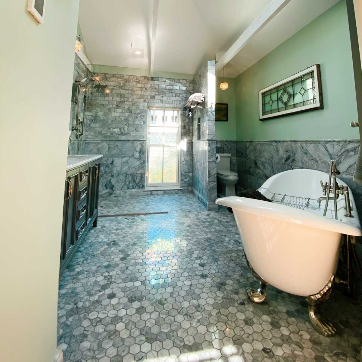 A modern bathroom with a freestanding bathtub, hexagonal tile flooring, and a skylight illuminating the space.