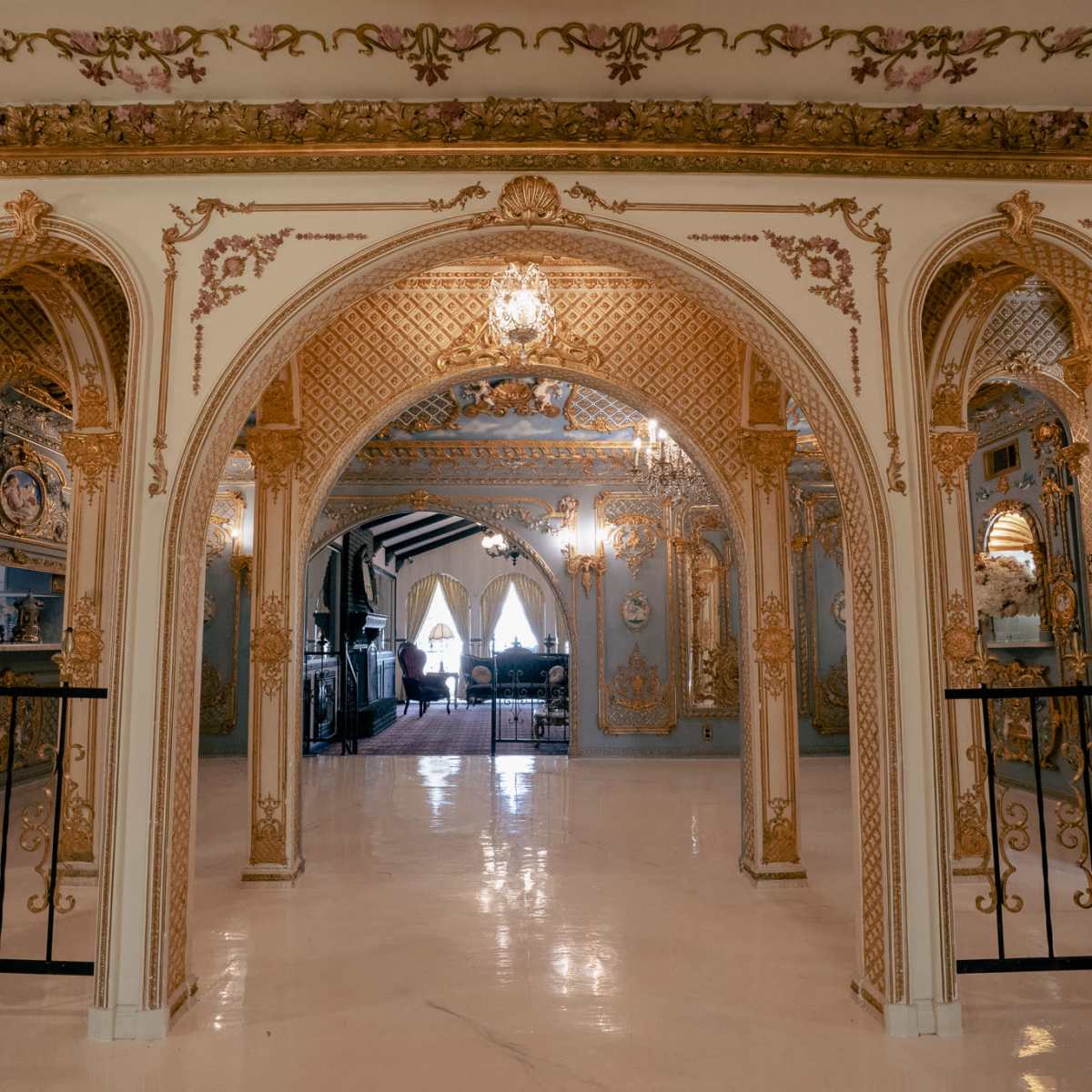 A lavishly decorated interior featuring ornate arches and intricate gold detailing on the walls and ceiling.