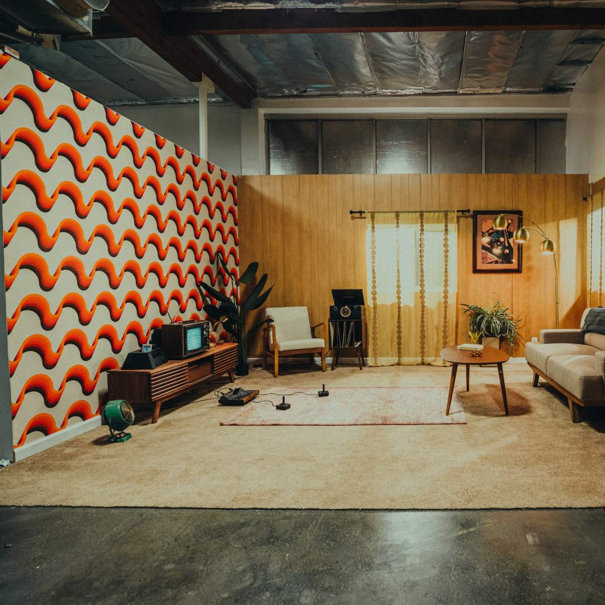A retro-inspired living room with a patterned wall, a sofa, a coffee table, and various decorative elements.