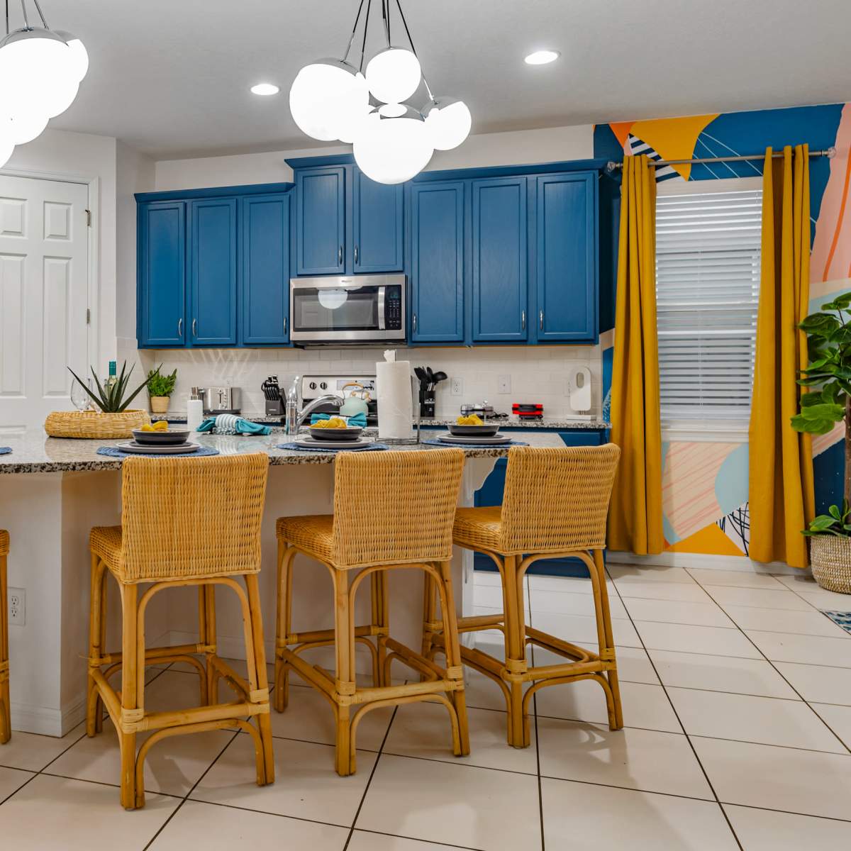 A modern kitchen featuring blue cabinetry, stainless steel appliances, and a large island with wicker bar stools.
