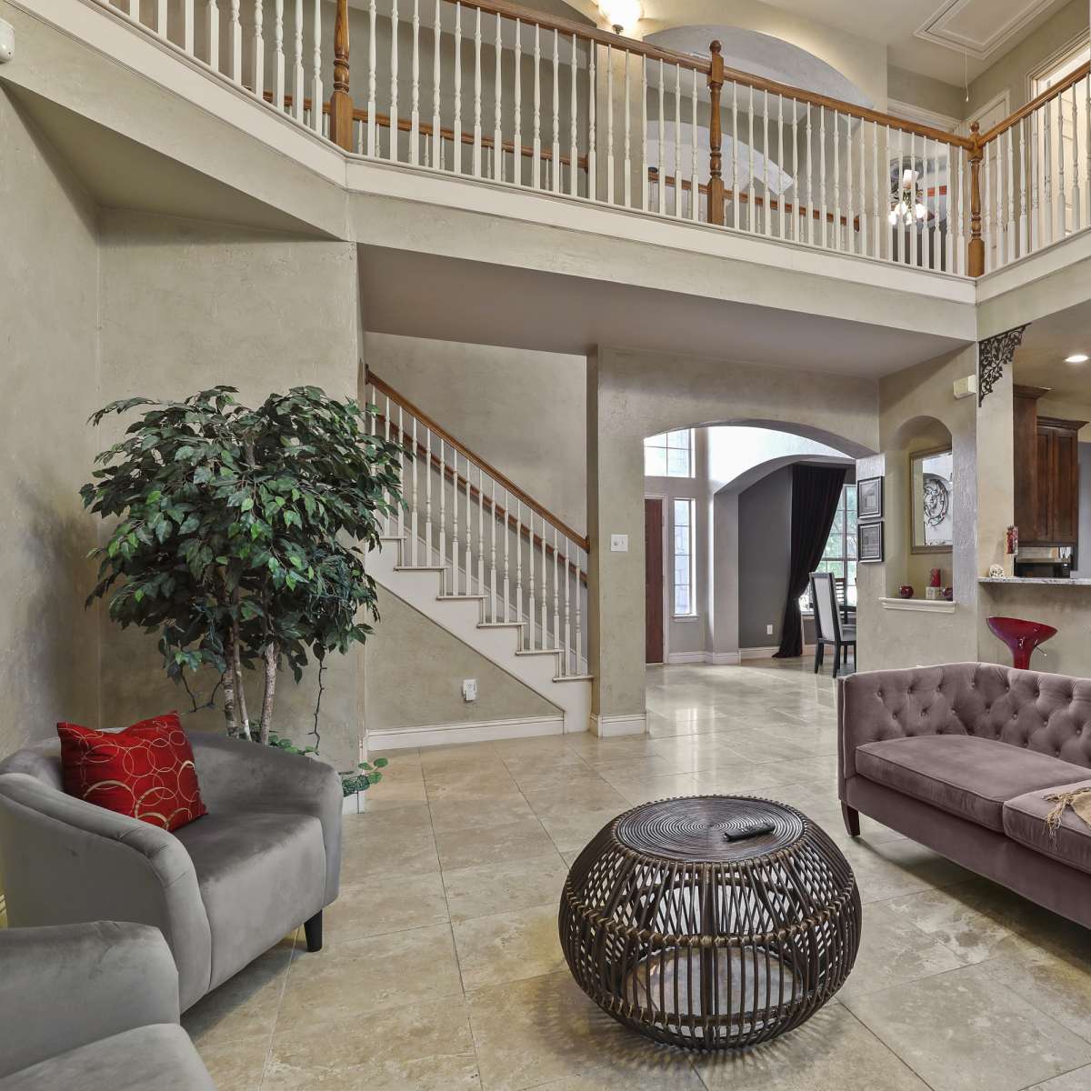 A spacious living area with a staircase, a modern couch, and a dining space visible in the background.