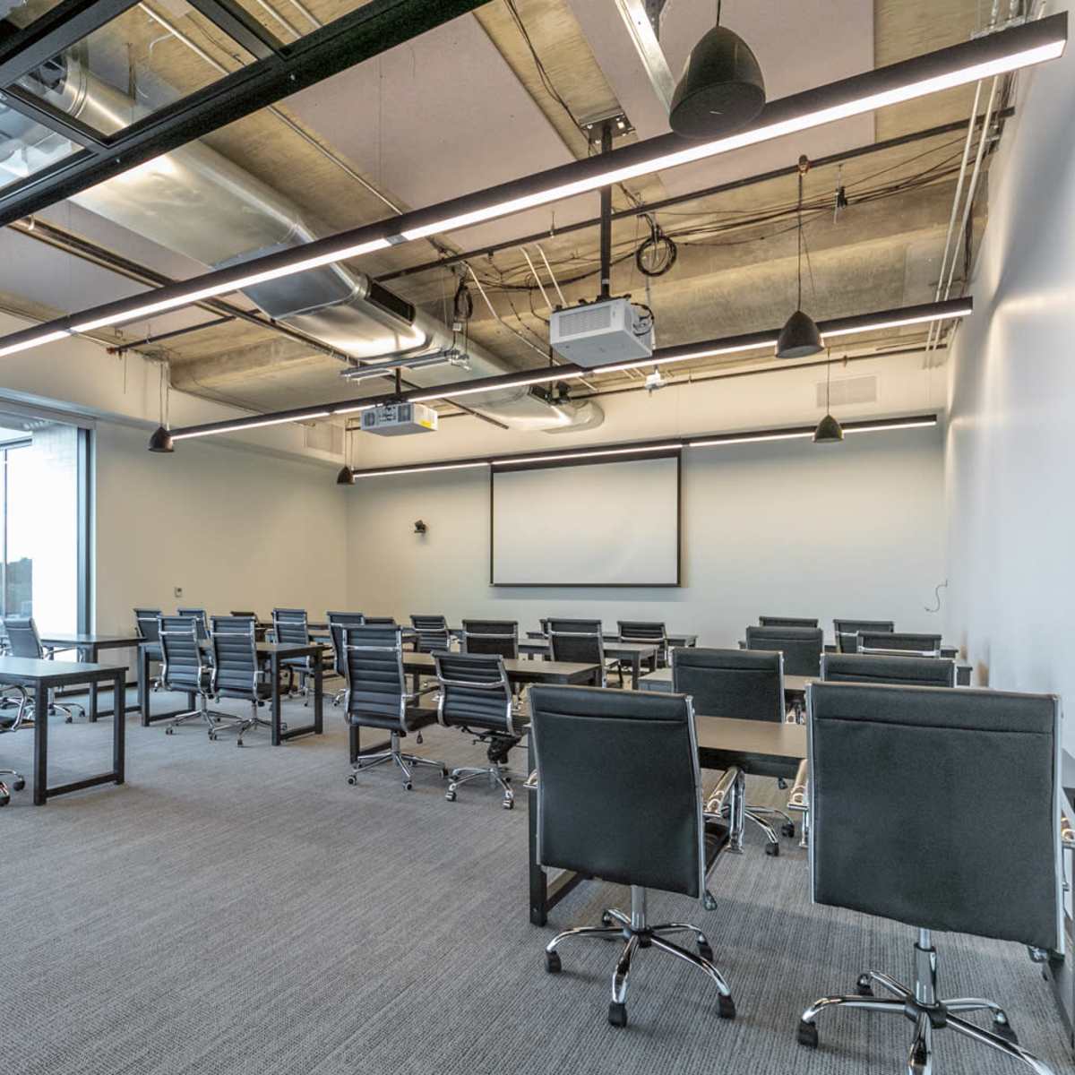 A modern conference room with several tables arranged for meetings and large windows letting in natural light.