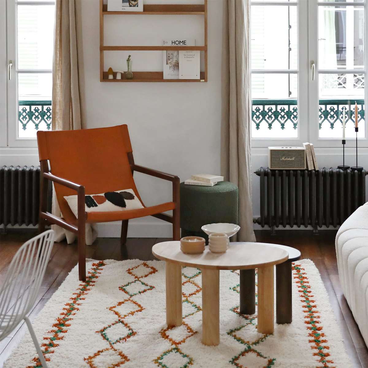 A modern living room featuring a white sofa, an orange armchair, a wooden coffee table, and a textured rug with geometric patterns.