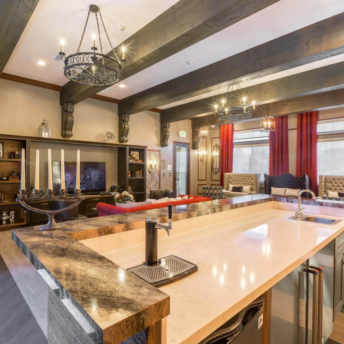 A modern kitchen and living area with a large island, leather sofas, and decorative lighting fixtures.