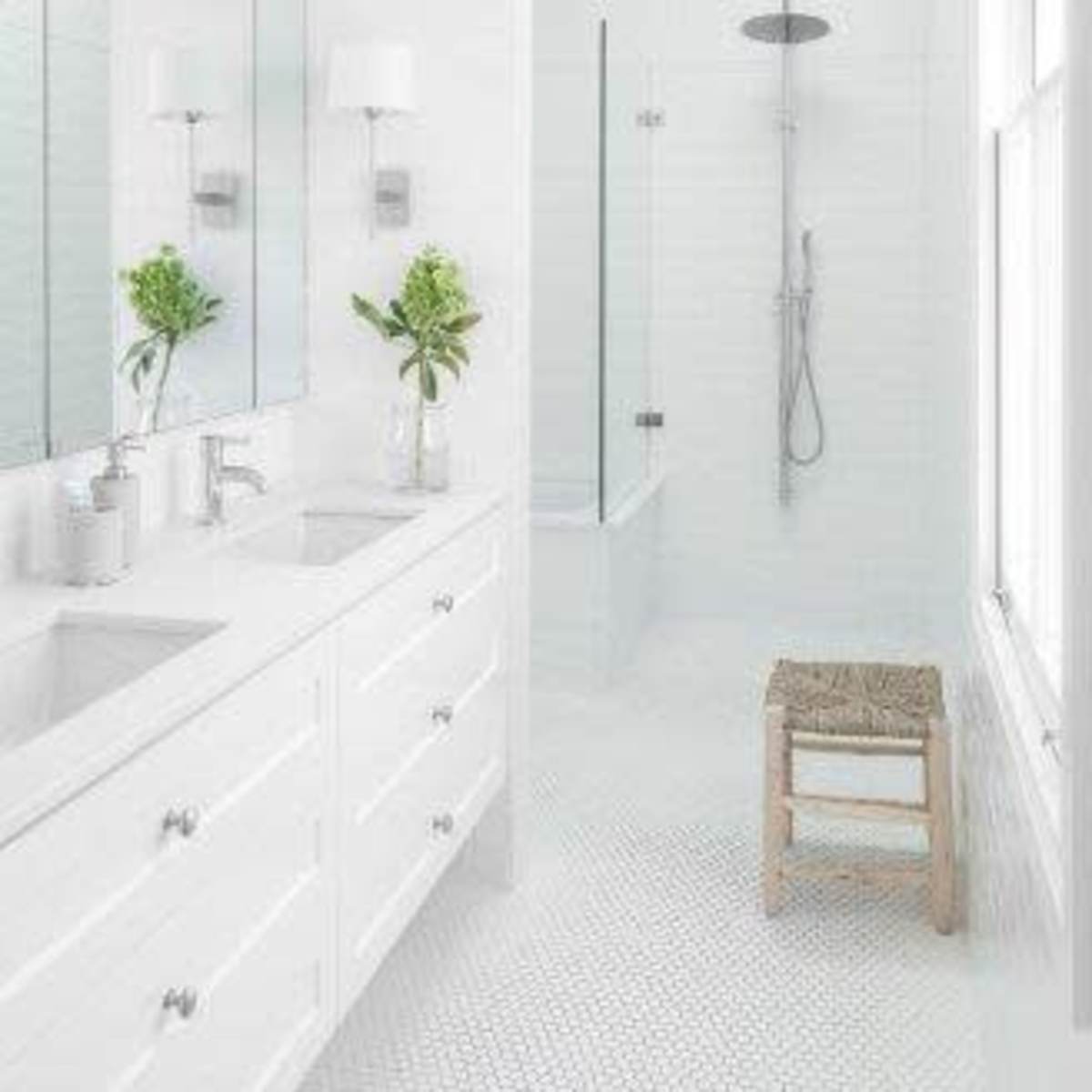 A bright, modern bathroom features a double sink vanity, a glass-enclosed shower, and a skylight.