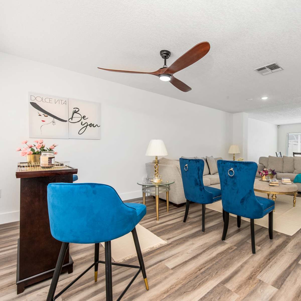 A contemporary living room with a seating area featuring a large couch, two blue chairs, and a decorative wall art piece.