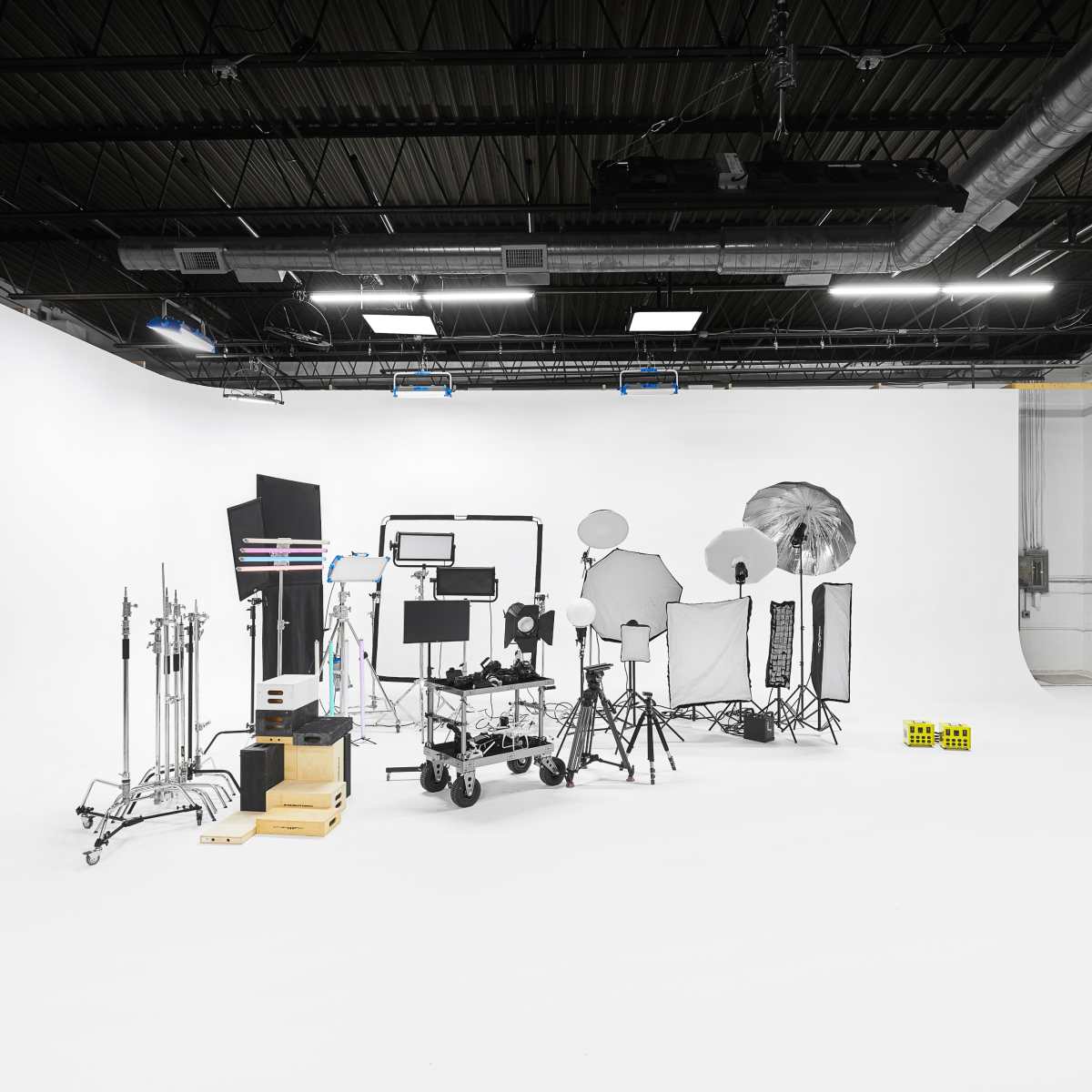 A photography studio is filled with various lighting equipment and backdrops arranged on a white floor.