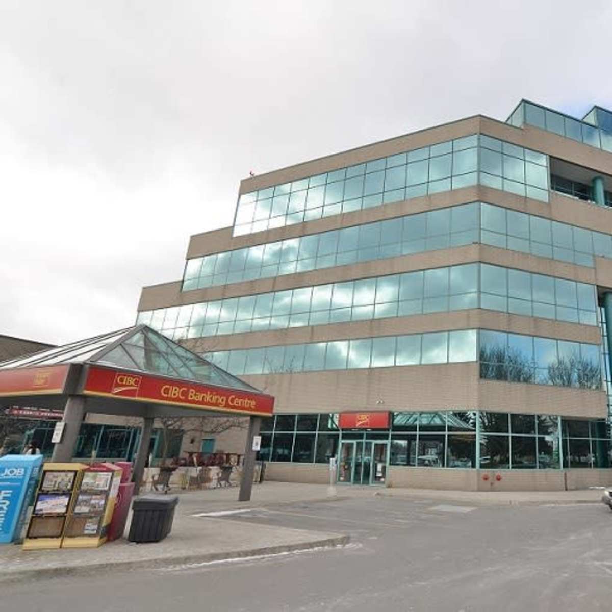 A modern bank building with a glass facade is situated next to a covered entrance marked "CIBC Banking Centre."