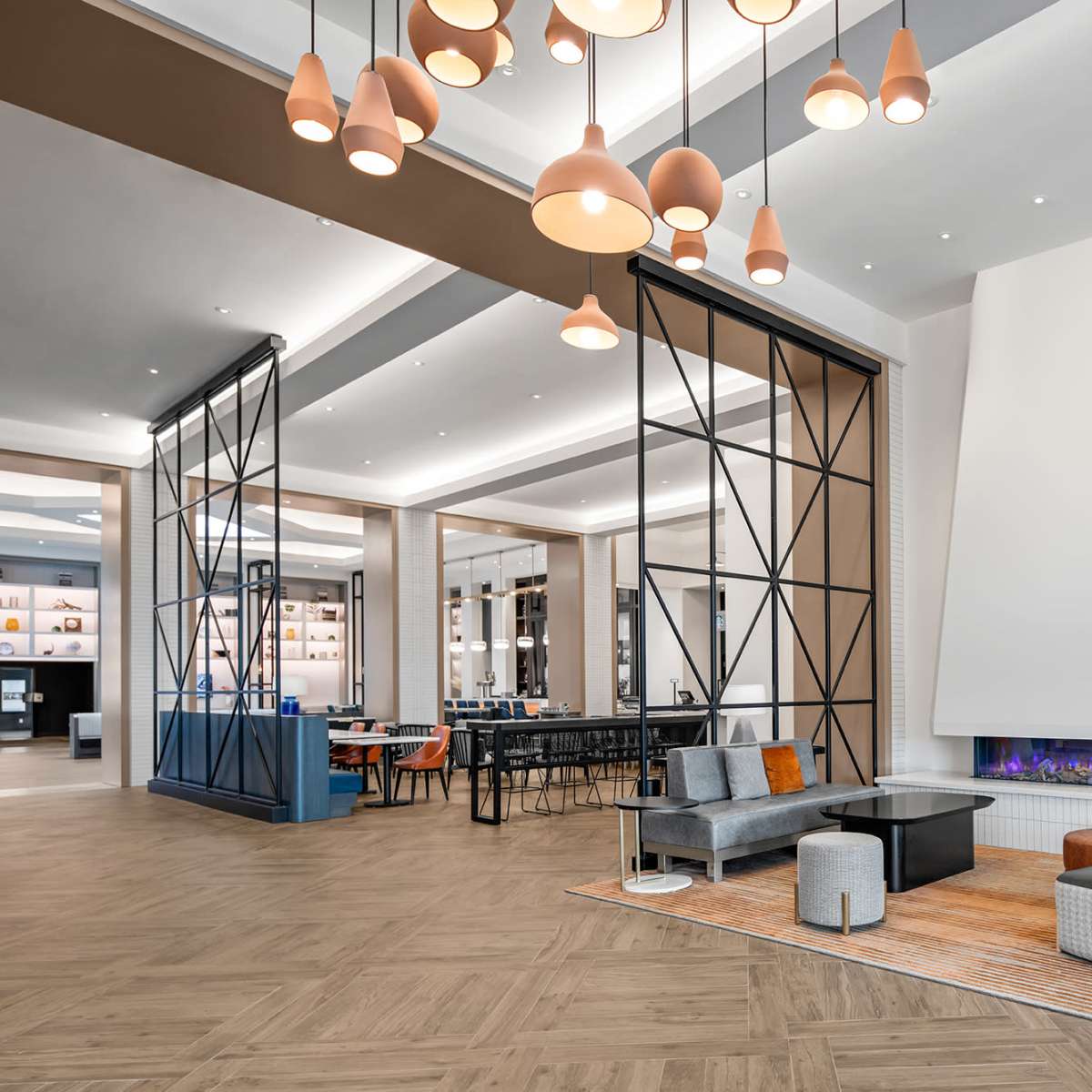 A modern lobby featuring a seating area with various chairs, a coffee table, and a white fireplace surrounded by decorative lighting fixtures.
