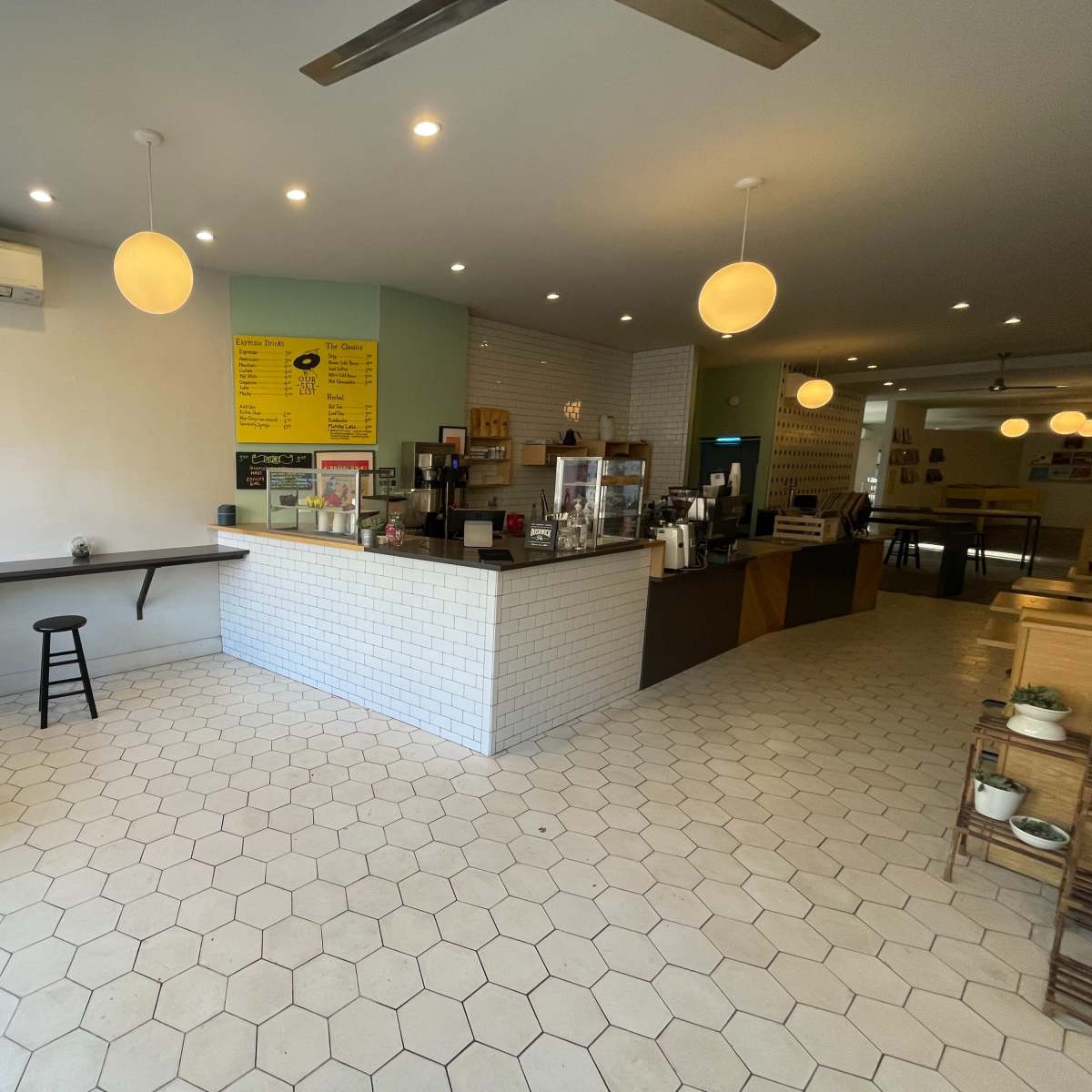A modern café interior with a payment counter, seating area, and hexagonal tiled flooring.