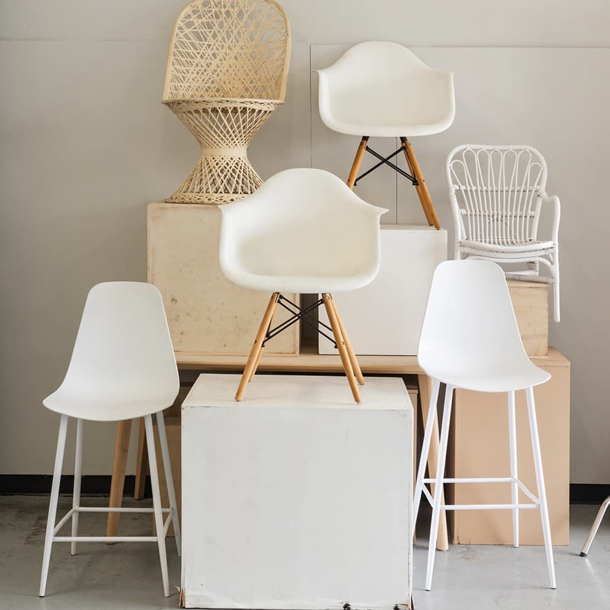 A collection of various chairs arranged on and around several stacked boxes in a minimalist setting.