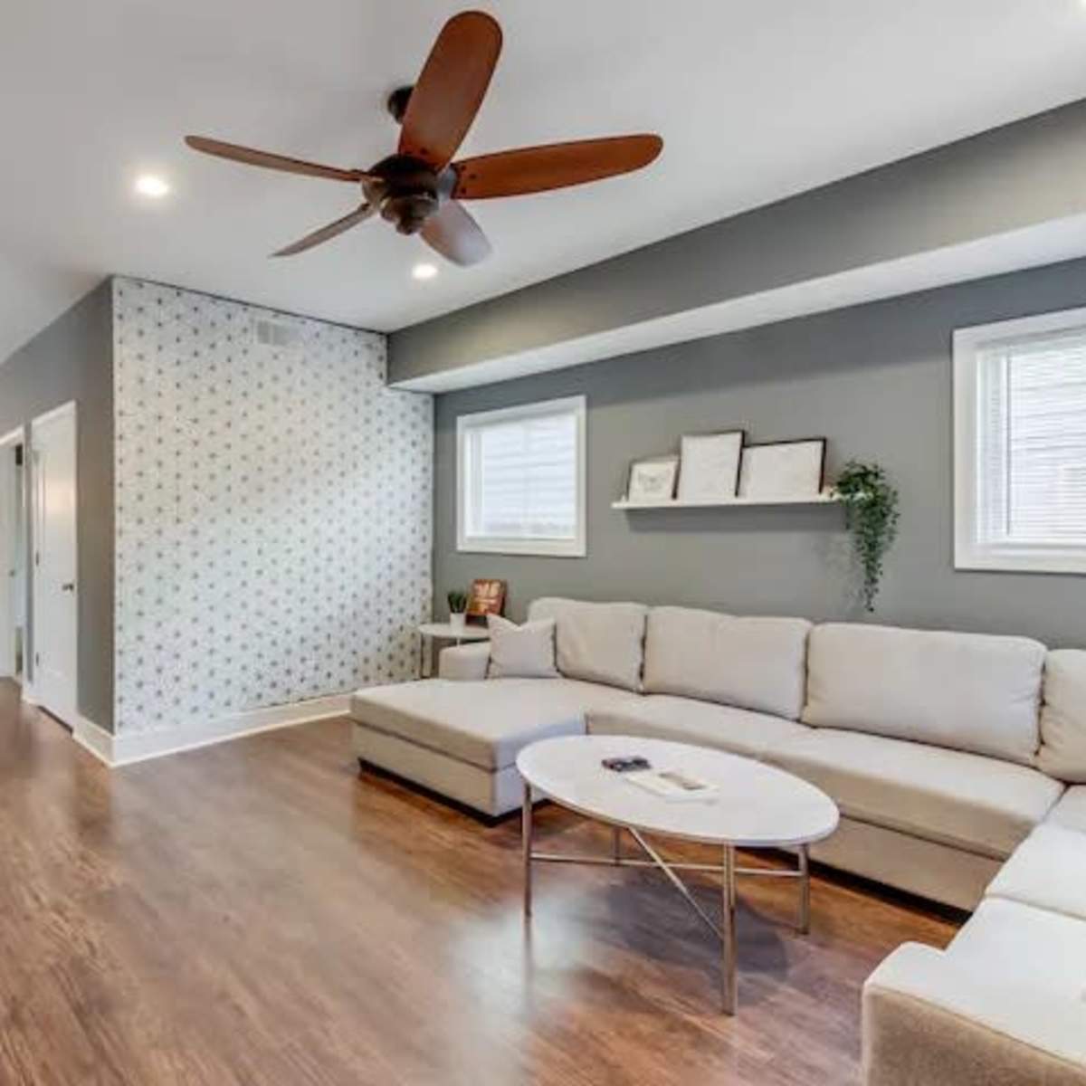 A modern living room with a sectional sofa, a round coffee table, and a view into a dining area and kitchen beyond.